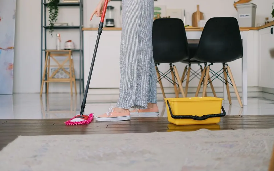 Floor being mopped with a bucket beside it in an empty flat